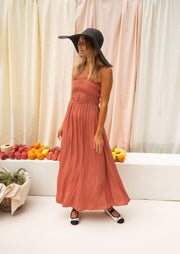 Robe bustier plissée devant portée par une femme, silhouette entière, chapeau, banc blanc