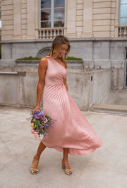Robe plissée à ouverture latérale portée par une femme, en marchant, bouquet, jupe plissée