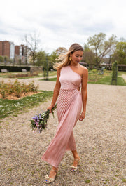 Robe plissée à ouverture latérale portée par une femme, vue de face, chemin, bouquet