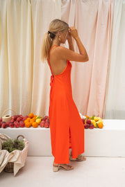 Robe satinée dos ouvert fendue portée par une femme, vue de dos, cheveux blonds, main dans les cheveux