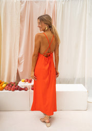 Robe satinée dos ouvert fendue portée par une femme, vue de dos, rideaux, fente