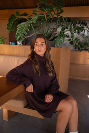 Robe pull à col roulé portée par une femme, assise, banquette en bois