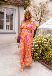 Robe lurex à manches courtes portée par une femme, vue de face, buissons fleuris, porte