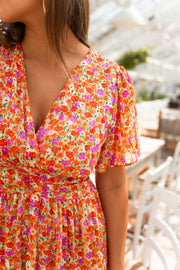 Robe lurex à manches courtes portée par une femme, vue rapprochée, décolleté V, imprimé fleuri