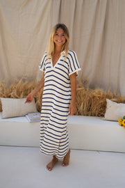 Robe longue rayée effet maille portée par une femme, vue de face, canapé blanc, pieds nus