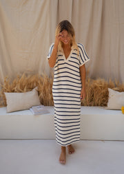 Robe longue rayée effet maille portée par une femme, vue de face, fond beige, fente