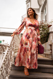 Robe longue à motifs dorés portée par une femme, silhouette entière, escalier, sac bordeaux