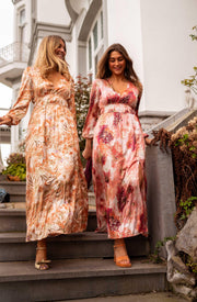 Robe longue à motifs dorés portée par deux femmes dans un escalier, robes fleuries