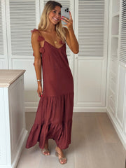Robe fluide à bretelles fleuries portée par une femme, vue de face, commode, volant bas