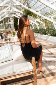 Robe à bretelles bijou portée par une femme, assise, fauteuil blanc, jambes croisées