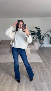 Pull col roulé beige — vue portée en pied, debout sur un parquet clair