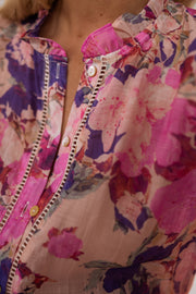Chemise fleurie manches longues portée par une femme, vue rapprochée, col boutonné, fleurs