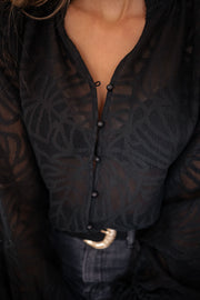 Blouse transparente à col V portée par une femme, vue rapprochée, col V boutonné