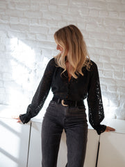 Blouse transparente à col V portée par une femme, vue de trois-quarts, regard de côté, jean gris