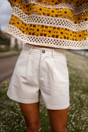 Short taille haute porté par une femme, vue rapprochée, short beige, haut crocheté jaune