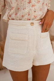 Short doublé effet tweed porté par une femme, vue rapprochée, poche, chemisier fleuri