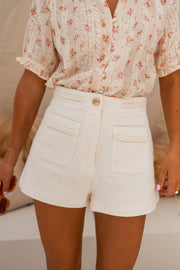Short doublé effet tweed porté par une femme, vue rapprochée, poches, bouton doré