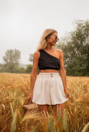 Short en coton légèrement évasé porté par une femme, silhouette entière, champ de blé doré, lunettes