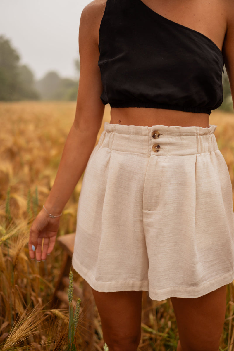 Short en coton légèrement évasé porté par une femme, vue rapprochée, boutons, taille haute
