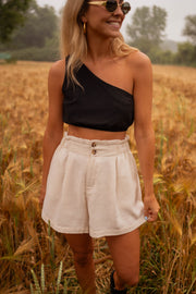Short en coton légèrement évasé porté par une femme, vue de trois-quarts, top noir asymétrique, lunettes