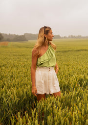 Short en coton légèrement évasé porté par une femme, silhouette entière, champ vert, top vert