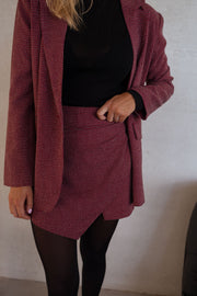 Jupe-short à carreaux drapée porté par une femme, vue rapprochée, blazer bordeaux, jupe-short