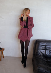 Jupe-short à carreaux drapée porté par une femme, silhouette entière, blazer bordeaux, bottes