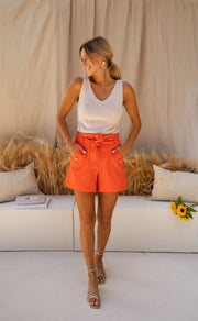 Short court à détails dorés porté par une femme, vue de face, canapé blanc, débardeur blanc