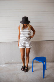 Short éponge rayé à poches porté par une femme, silhouette entière, chapeau noir, tabouret bleu