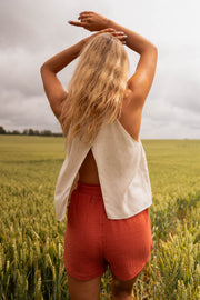 Short court à taille élastique porté par une femme, vue de dos, mains dans les cheveux, top crème