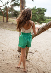 Top à fines bretelles porté par une femme, vue de dos, sable, short vert