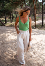 Top en maille décolleté V porté par une femme, silhouette entière, sable, pantalon blanc