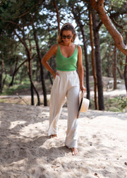 Top en maille décolleté V porté par une femme, silhouette entière, pins, pantalon blanc