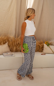 Pantalon fluide à motif tie-dye porté par une femme, vue de profil, banc, sac vert