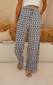 Pantalon fluide à motif tie-dye porté par une femme, vue rapprochée, motif géométrique, sandales