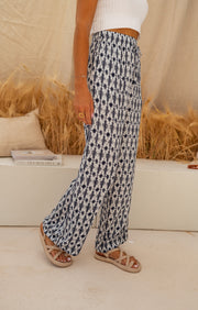 Pantalon fluide à motif tie-dye porté par une femme, vue de trois-quarts, sandales, balles de foin