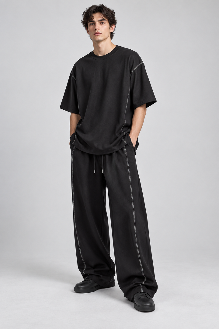Modelo adulto com conjunto preto de camisola e calças amplas, vista frontal.