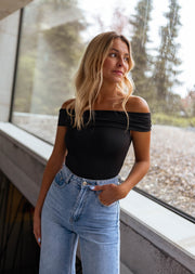 Body bustier à épaules dégagées porté par une femme, silhouette entière, rebord, fenêtre