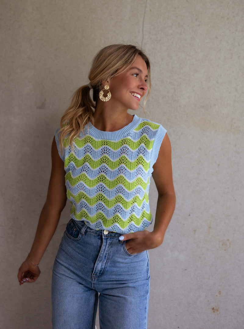Top crochet ajouré col rond porté par une femme, vue de trois-quarts, mur beige, jean
