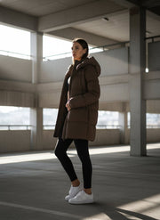 Veste matelassée brune à capuche — vue portée en extérieur.