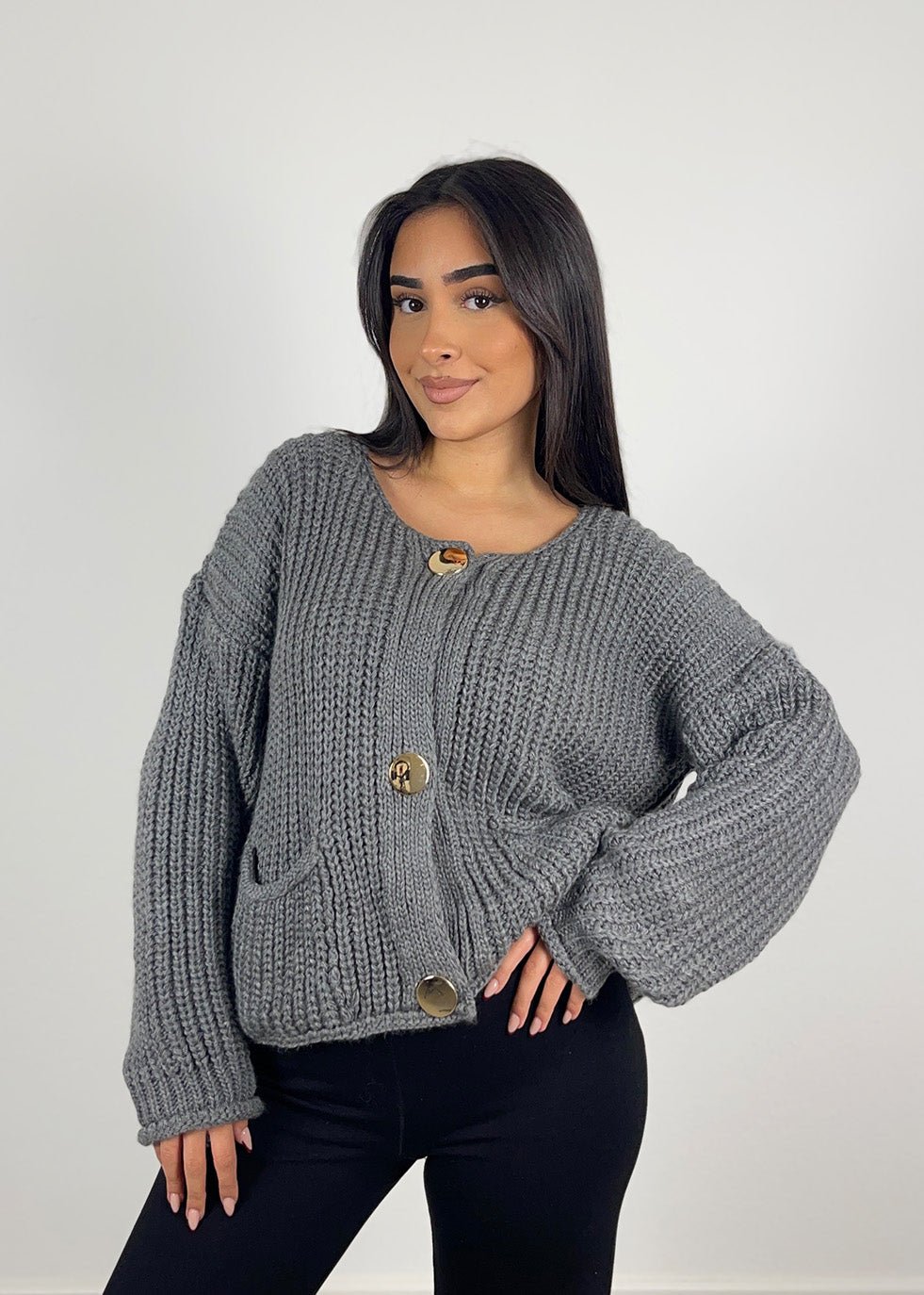 Cardigan maille gris à boutons — vue portée de face, cadrée à la taille, sur un haut sombre