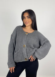 Cardigan maille gris à boutons — vue portée de face, cadrée à la taille, sur un haut sombre
