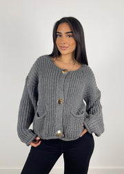 Cardigan maille gris à boutons — vue portée de trois-quarts, une main près de la poche
