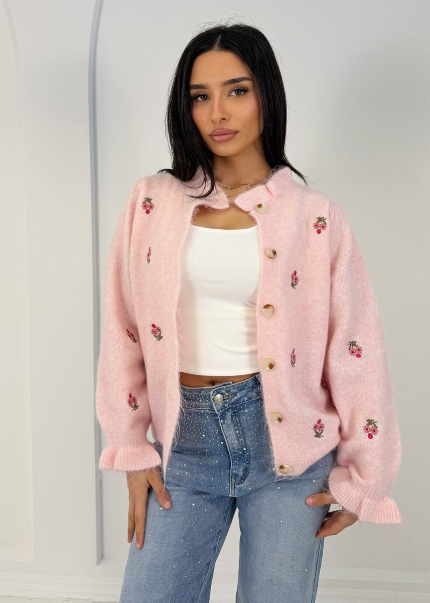 Cardigan maille motif floral rose — vue portée de face, cadrée à la taille, sur un haut blanc et jean clair