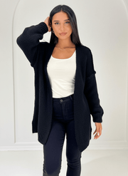 Cardigan beige à structure douce — vue portée de face, version noire sur un haut blanc