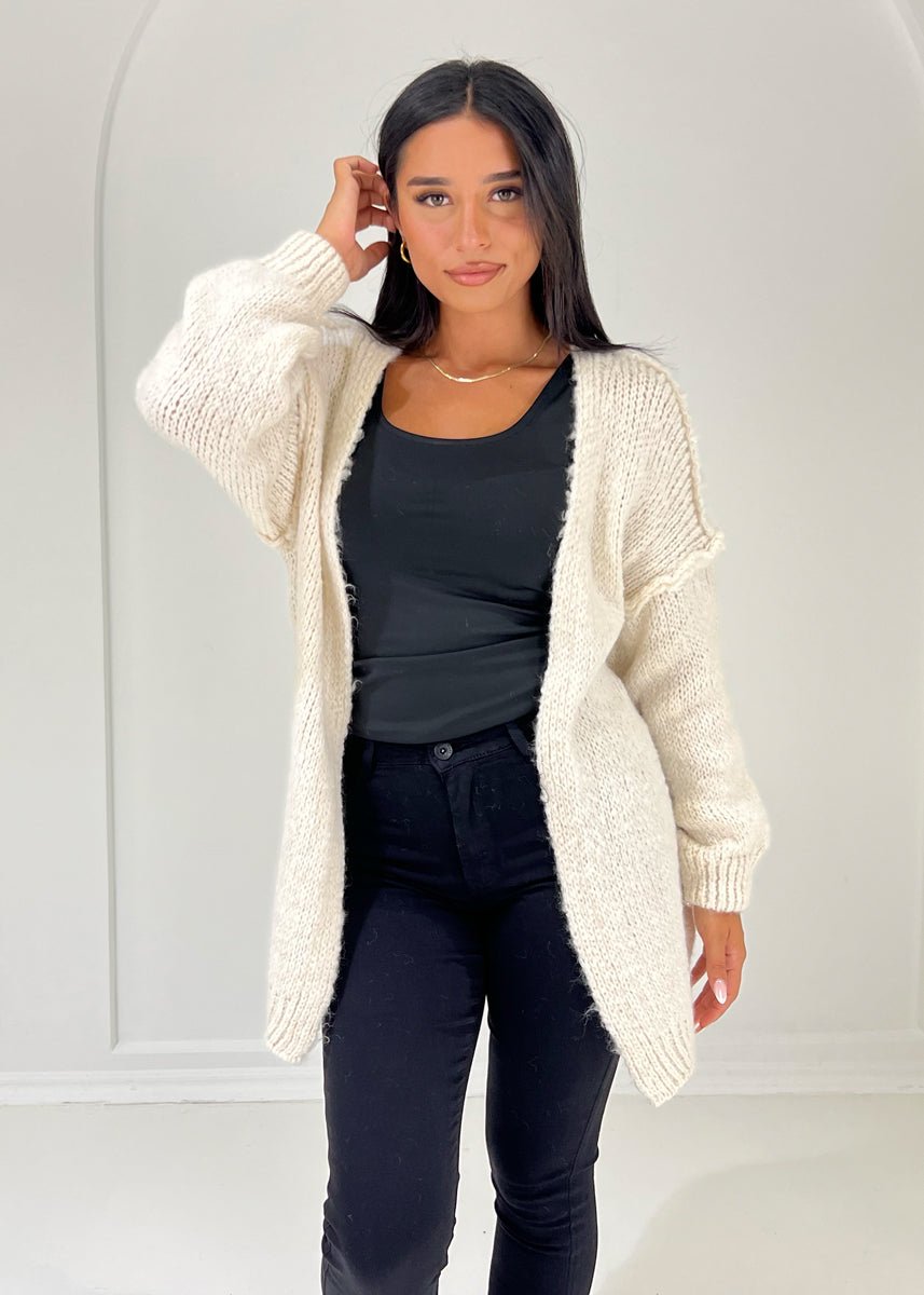 Cardigan beige à structure douce — vue portée de face, cadrée à la taille, long cardigan ouvert sur un haut noir