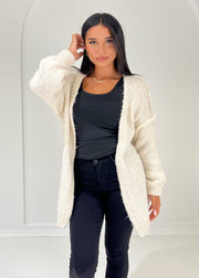 Cardigan beige à structure douce — vue portée de face, cadrée à la taille, long cardigan ouvert sur un haut noir