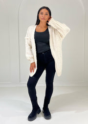 Cardigan beige à structure douce — vue portée en pied, mains dans les poches