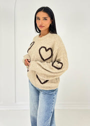 Pull beige à motif cœurs — vue portée de profil, cœurs sur la manche
