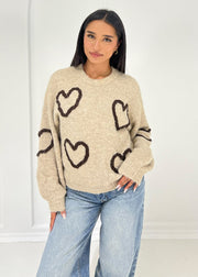 Pull beige à motif cœurs — vue portée de face, rentré dans un jean clair